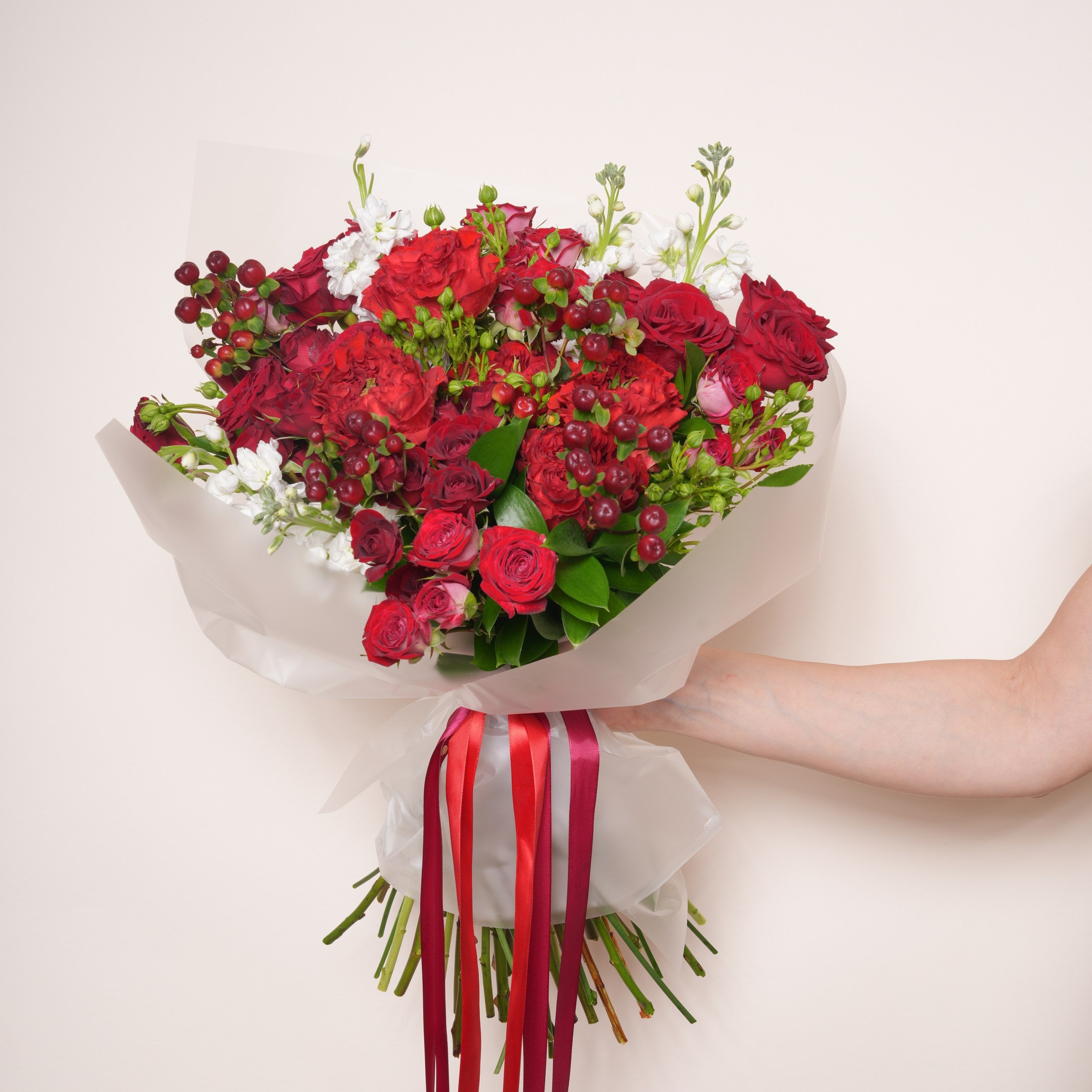 Granatina luxury bouquet — detail of garnet red baby roses against green foliage and white stock | Ecoroses Los Angeles